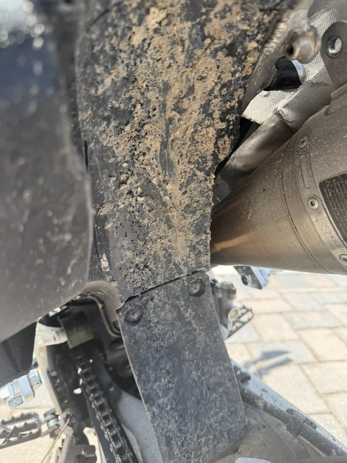 Blue motorcycle rear fender before detailing, heavily covered with dried mud