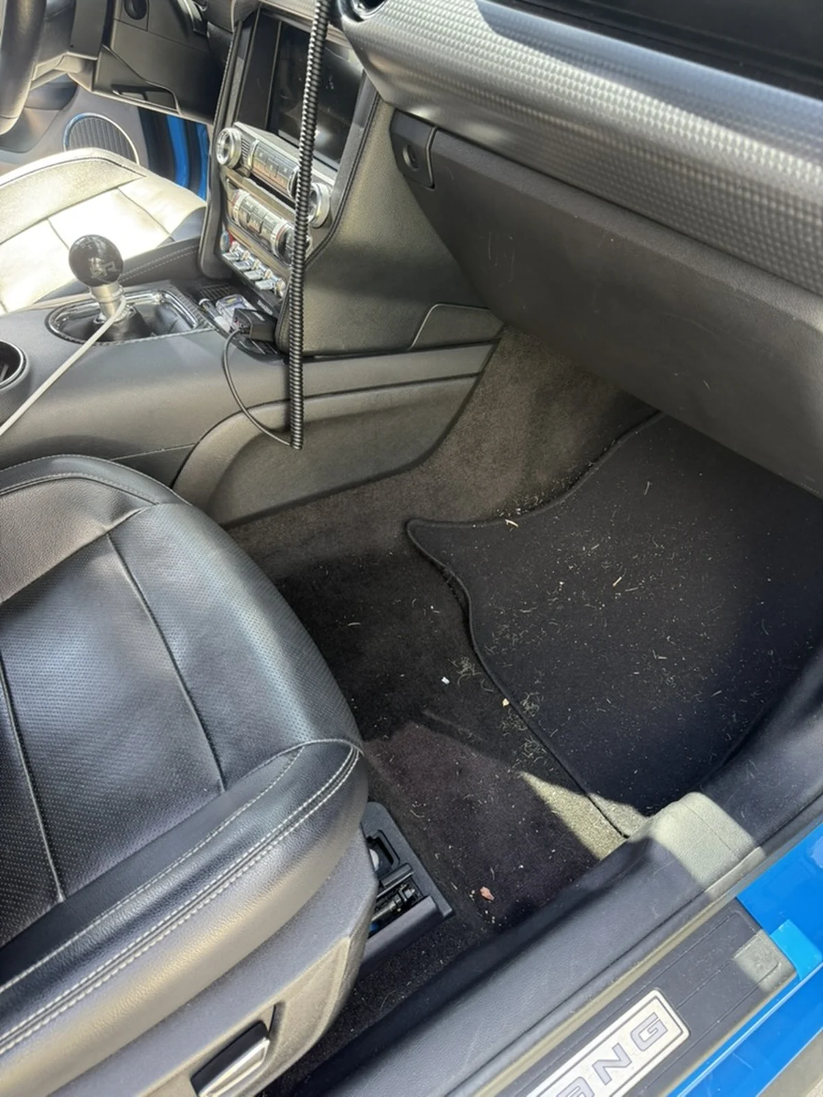 Blue Ford Mustang passenger floor before detailing, with visible dirt and loose debris