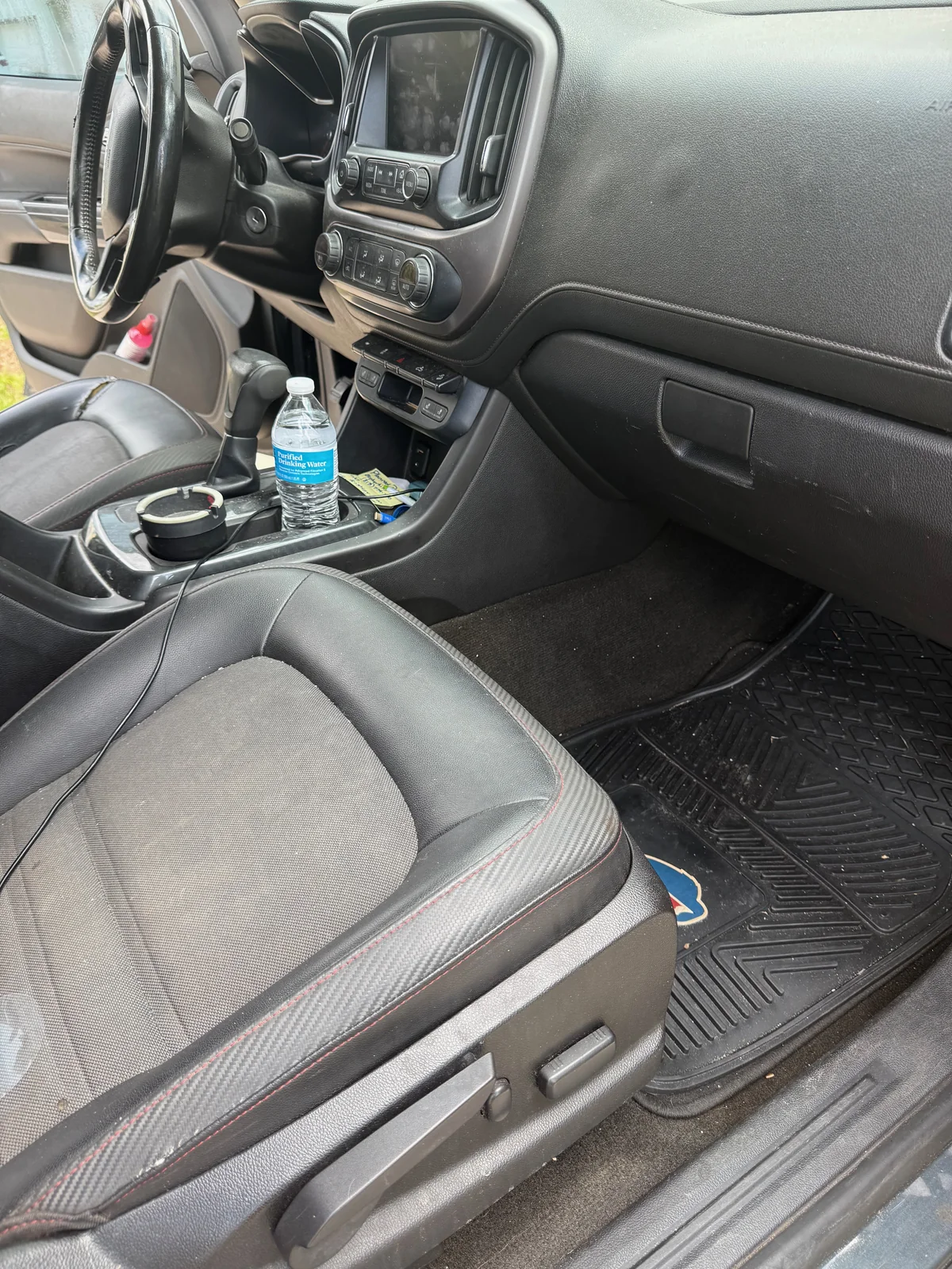 GMC pickup front passenger area before detailing, with clutter and a dirty floor mat