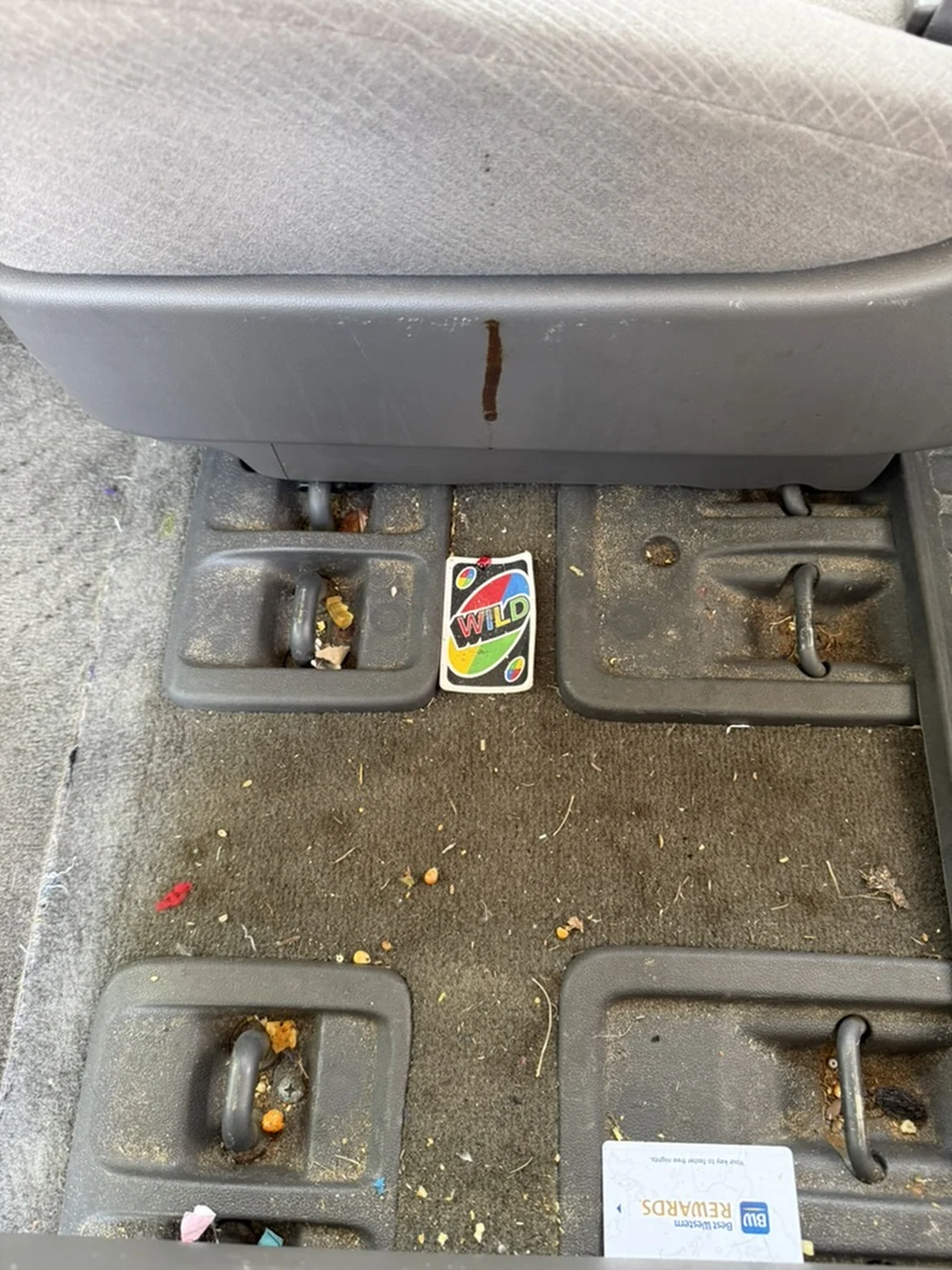 Honda Odyssey carpet and seat-mount tracks before detailing, with heavy crumbs and debris