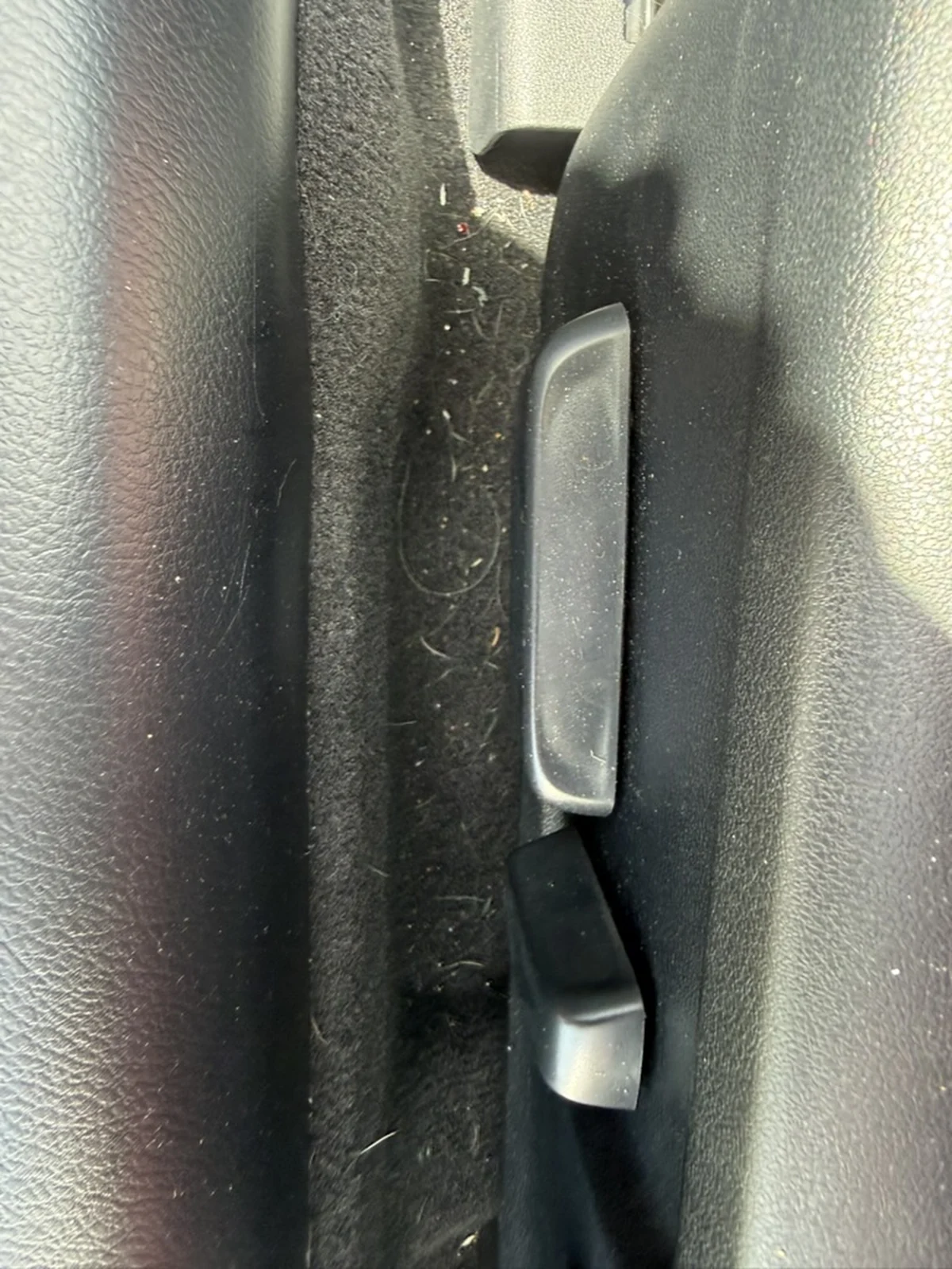 Lexus RC 350 carpeted gap beside the seat controls before detailing, with hair and debris